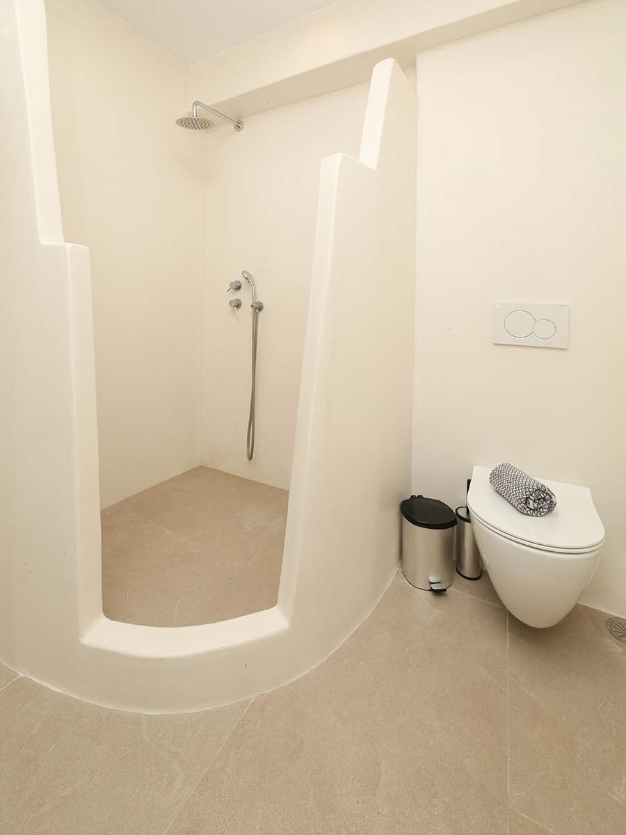Μπάνιο της One-Bedroom Villa με χτιστό ντους και minimal κυκλαδίτικο σχεδιασμό