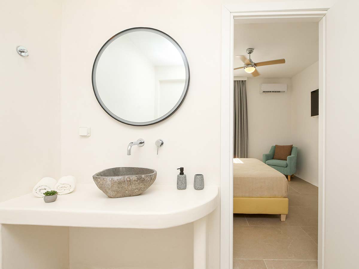 Μπάνιο της One-Bedroom Villa με πέτρινο νιπτήρα και θέα προς το υπνοδωμάτιο